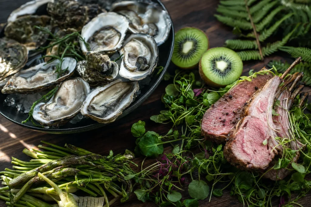 Nature morte gastronomique avec huîtres, agneau, kiwis et légumes locaux sur planche en bois