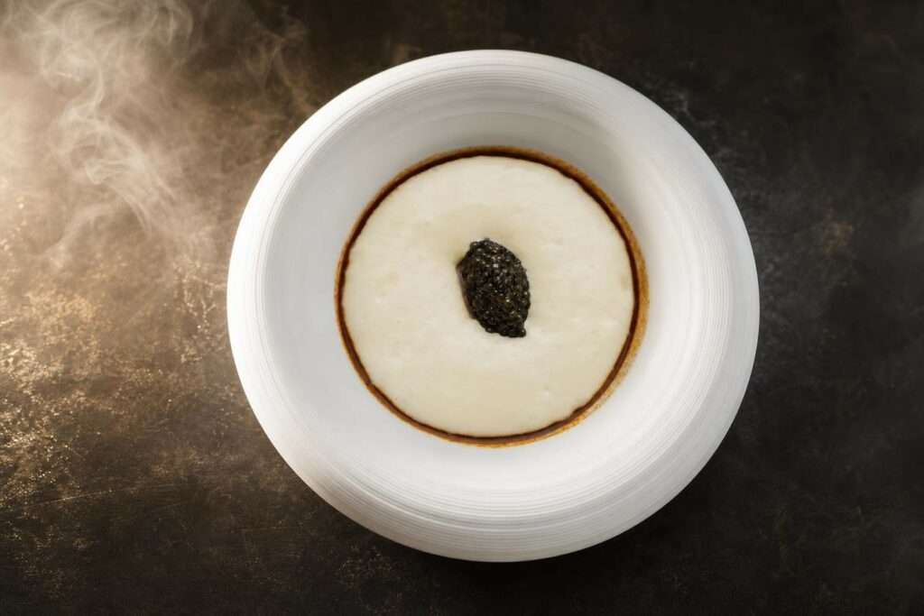 Illustration photographique évoquant l’excellence culinaire par une vapeur légère sur métal sombre