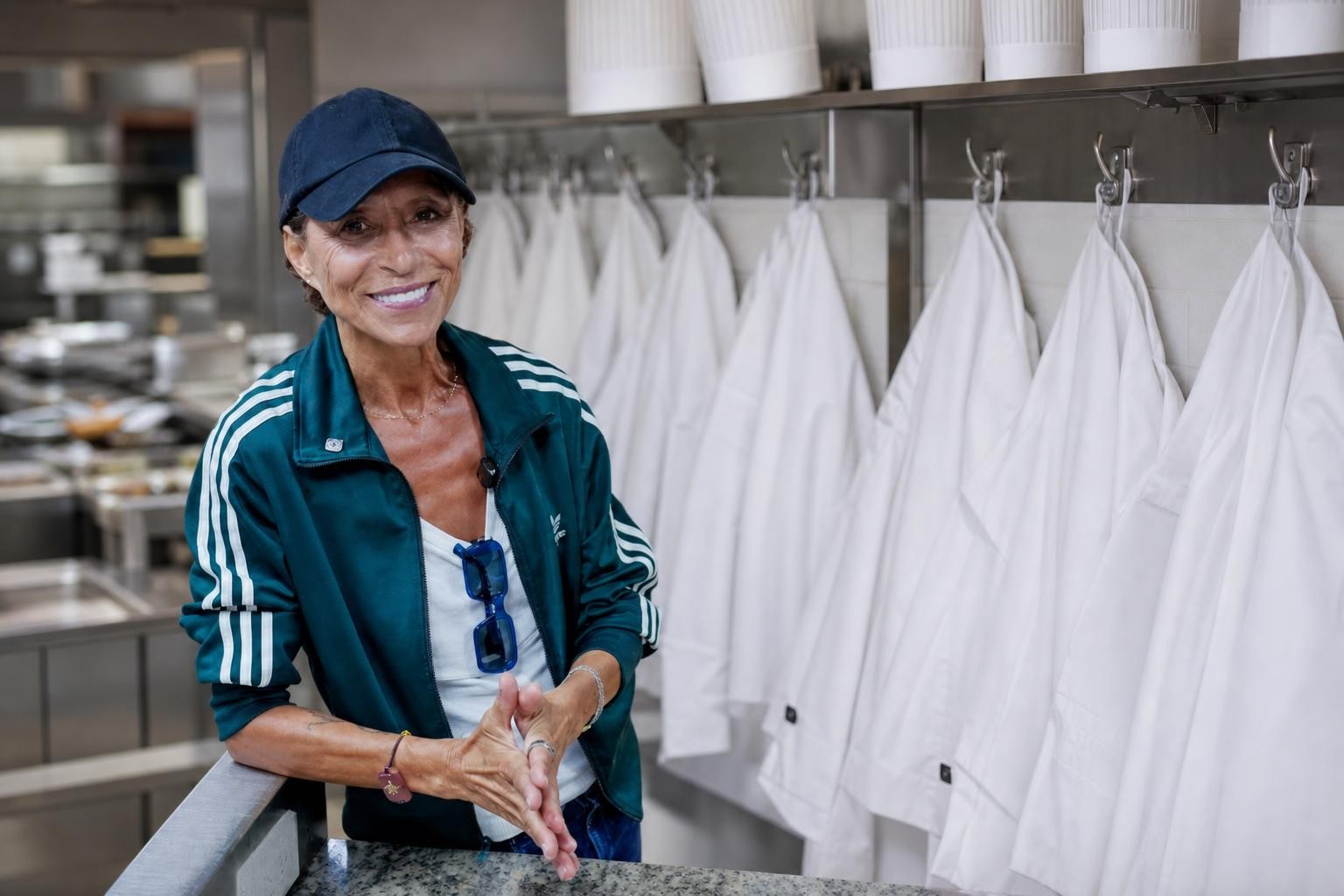 Vestes de chef blanches suspendues évoquant l’appel pour les femmes chefs Scène évocatrice de vestes de chef et toques alignées pour illustrer la reconnaissance des femmes chefs
