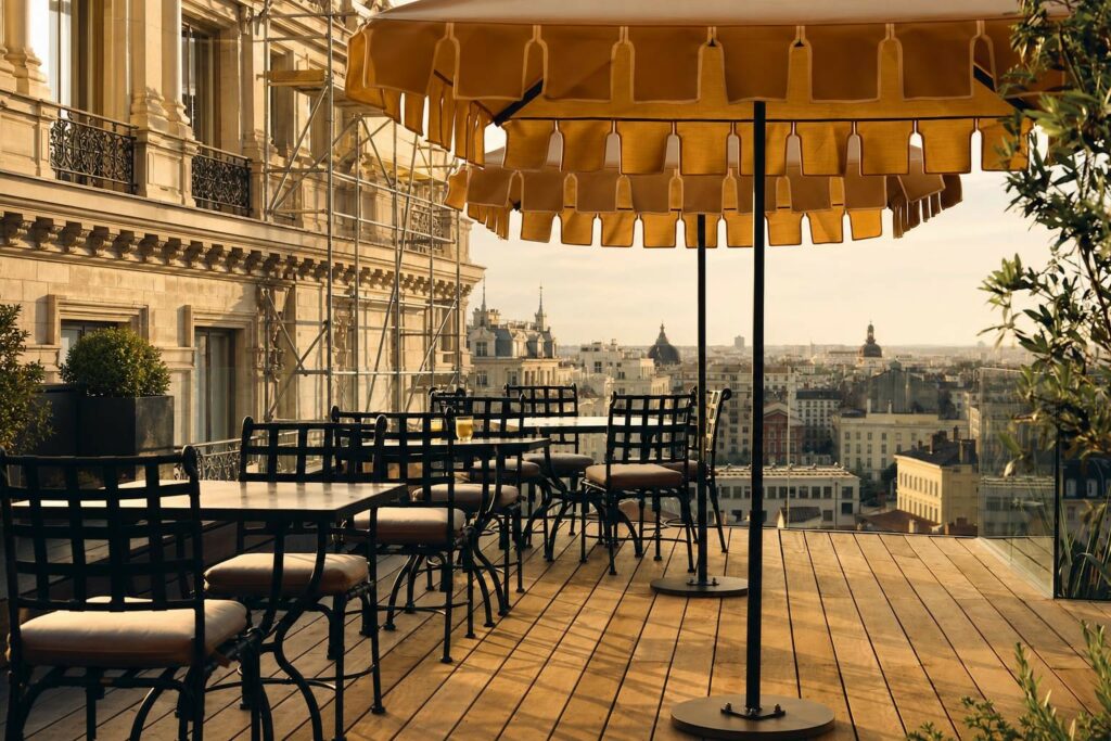 Façade en pierre claire d’un hôtel classique avec échafaudage partiellement retiré, lumière dorée, architectural générique
